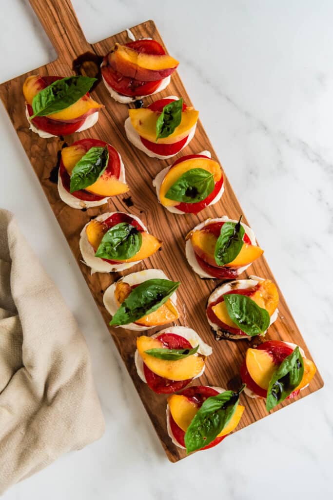 stacks of peach caprese on wooden cutting board